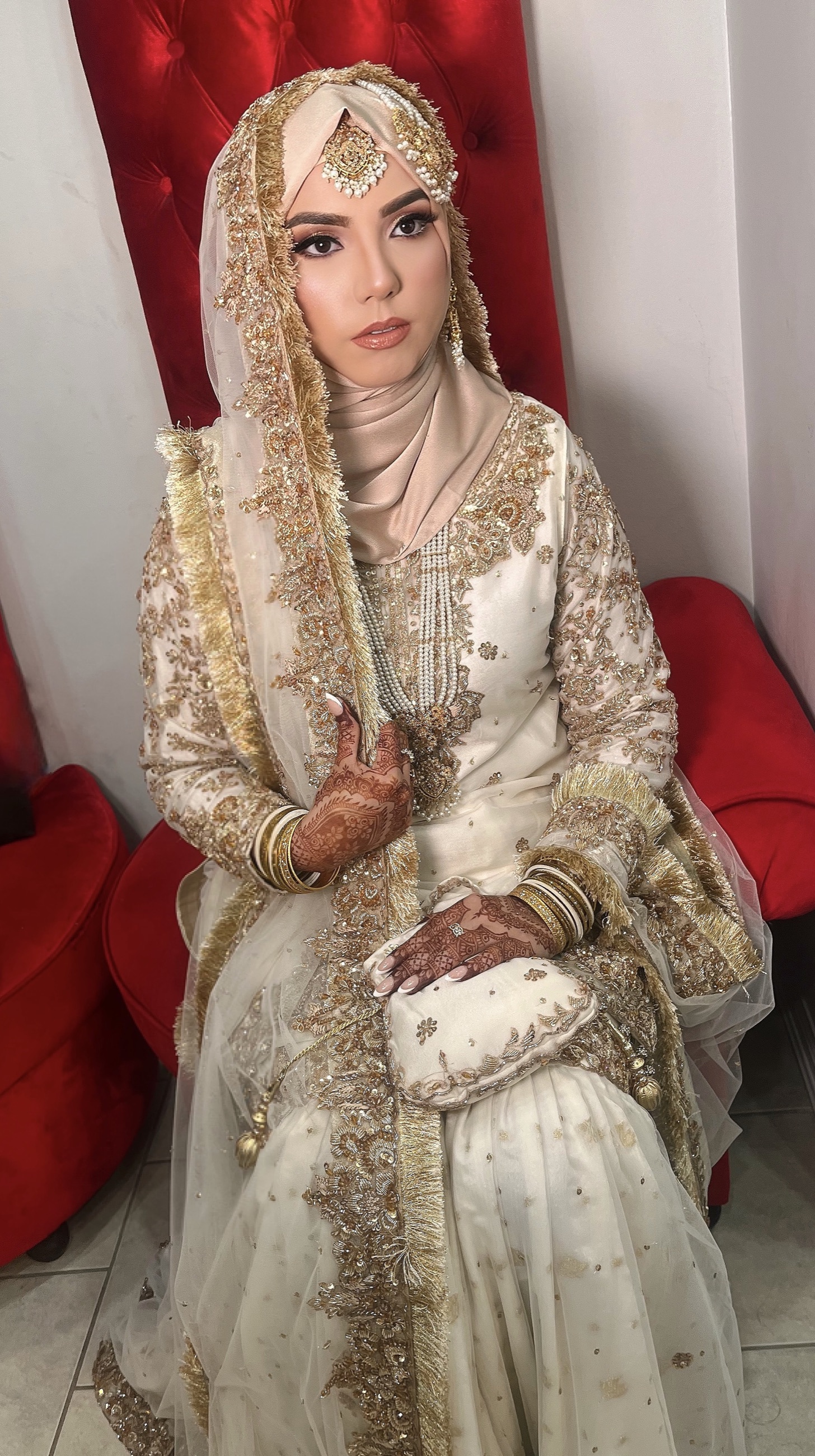 Bride in an ivory and gold hijab with finished bridal makeup
