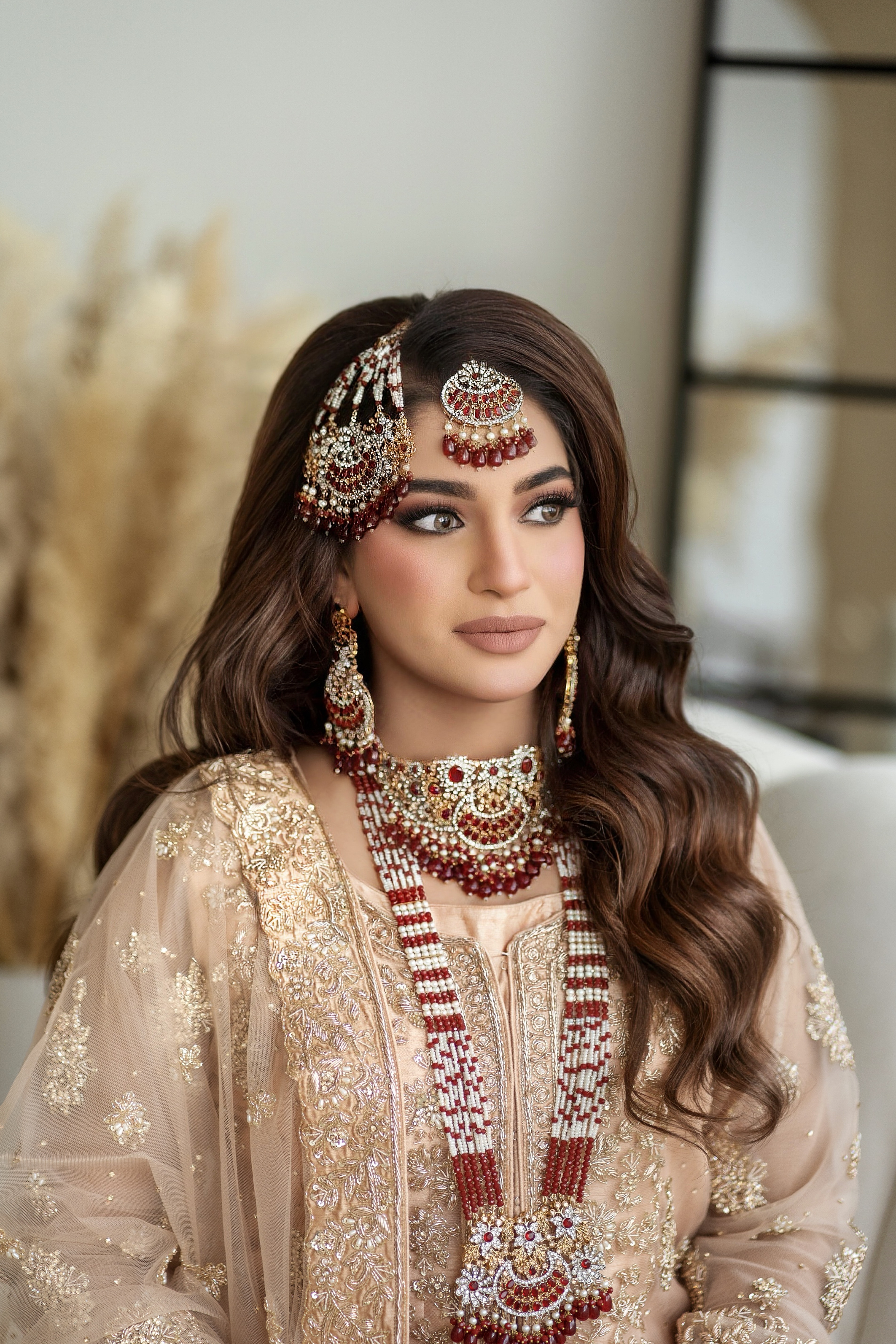 Luminous cream bridal look with sculpted waves and red jewellery